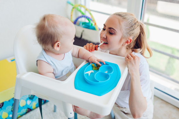 妈妈在家里教小宝贝吃水果。家人一起吃饭。婴儿坐在椅子上让孩子学习图片下载