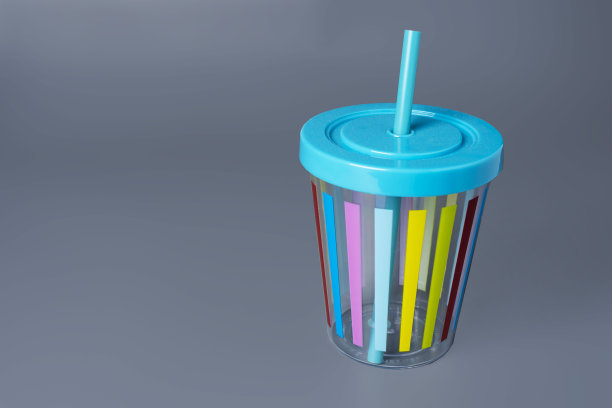 色彩鲜艳的杯子，灰色背景上有一根吸管图片下载