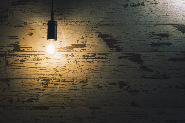 在黑暗中，古老的灯泡悬挂在风化的木墙上图片下载