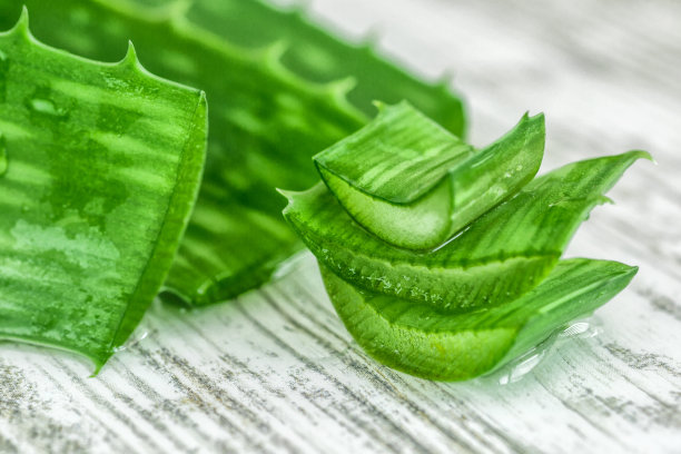 木制背景上有果肉的芦荟片。芦荟精油或含有芦荟切片的血清。护肤护发理念。芦荟叶片滴图片下载