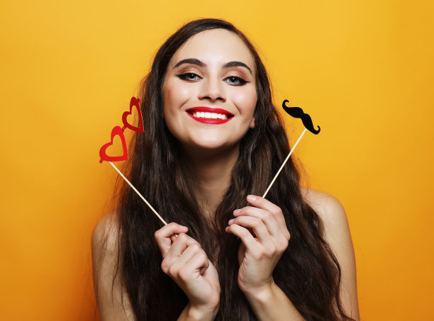 顽皮的年轻女子准备派对在黄色背景图片下载