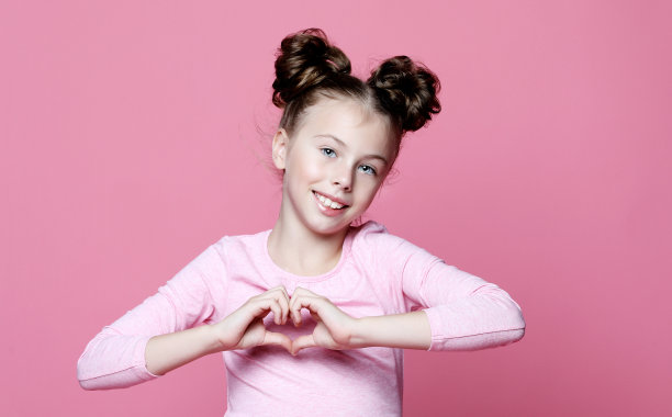 女孩在爱中微笑，用手展示心形符号和形状图片下载