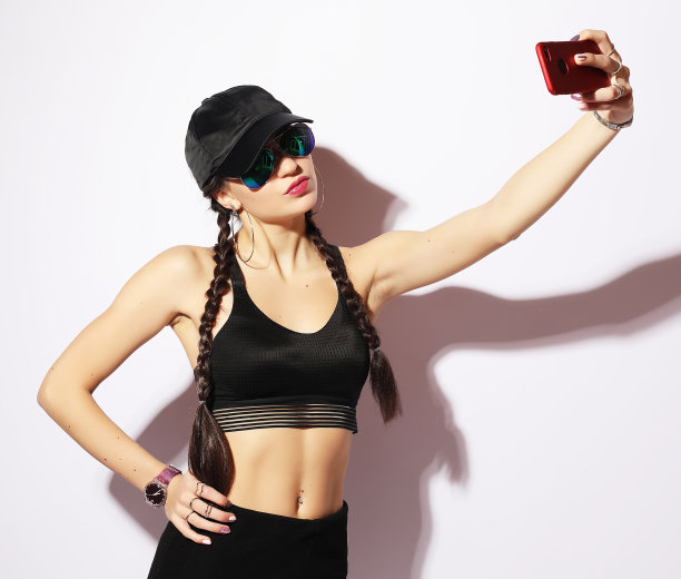 一名女子用手机自拍，手机被隔离在一台白色bac上图片下载