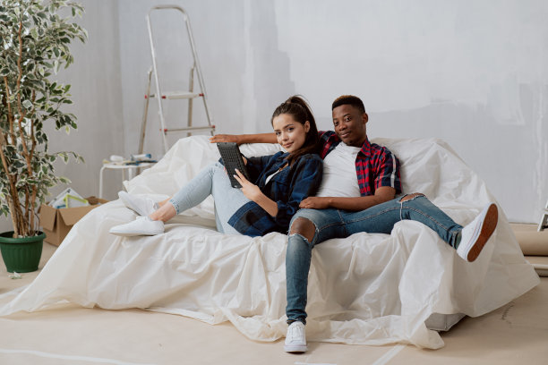 喜笑盈天的年轻学生租了一套新公寓，重新装修房间，舒舒服服地躺在用箔固定的沙发上，迷人的黑发靠在沙发上的黑皮肤男孩图片下载