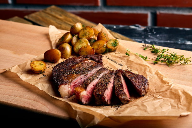美味新鲜，多汁的肋眼牛排，木桌上的大理石牛肉和小土豆图片下载