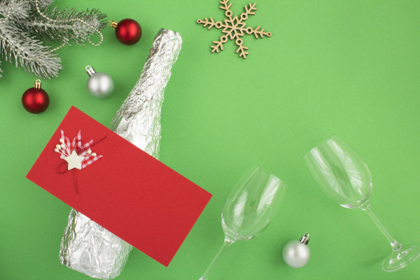 圣诞构图，银箔装香槟，绿色背景上有两个葡萄酒杯图片下载