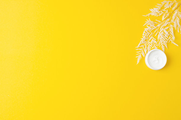 一罐黄色背景上有花的化妆品。平铺，复制空间图片下载