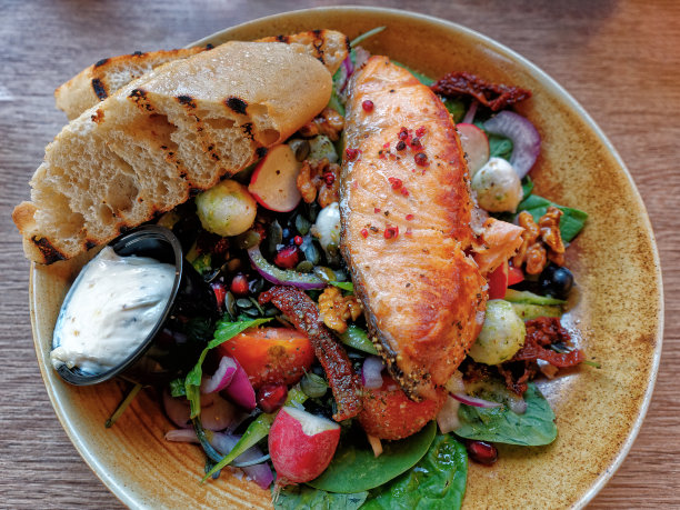 健康均衡午餐-烤红鱼片三文鱼和西红柿，黄瓜，橄榄，羊乳酪洋葱，酱汁，面包顶部视图图片下载