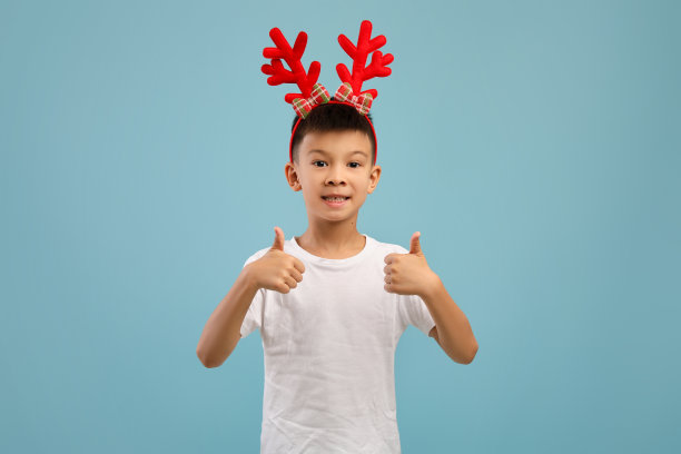 可爱的亚洲小男孩戴着驯鹿角，对着镜头竖起大拇指图片下载