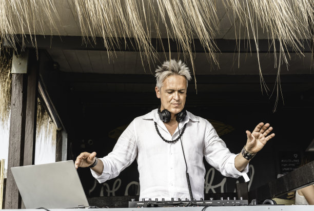 在海滩户外俱乐部派对上为游客播放音乐的音乐骑师-戴着耳机的Dj在音乐现场活动-现场活动，音乐和乐趣的概念-娱乐和派对的概念图片下载