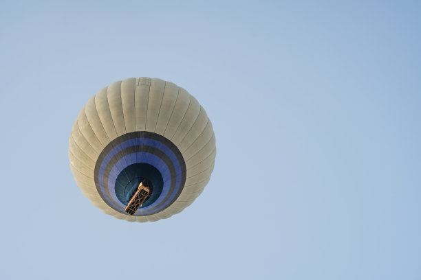 热气球在蓝色的天空飞行，带着一个由灰色织物制成的打开的降落伞和一个篮子。底部视图。乐趣和幸福。放松的飞行。本空间图片下载