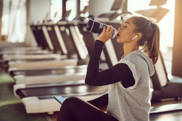 年轻的运动女子在体育馆里进行运动训练时喝水。图片下载