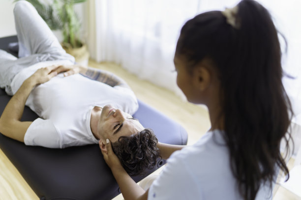 年轻女性物理治疗师在物理诊所与客户图片下载