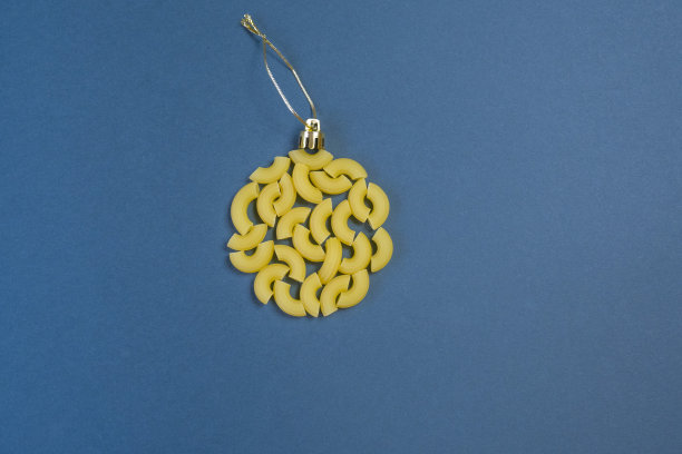 圣诞树上装饰成球状的意大利面，背景为蓝色的纸，俯视图。概念上的照片。图片下载