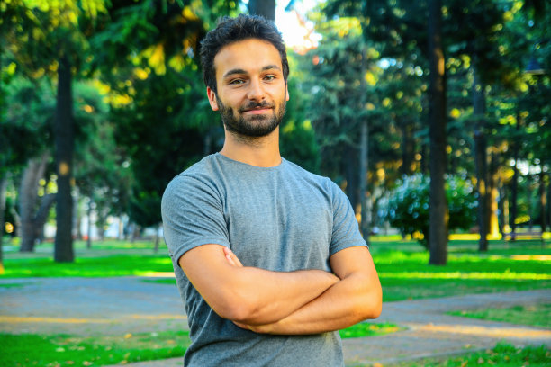 一名年轻男子在光天化日之下交叉着手臂对着镜头微笑图片下载