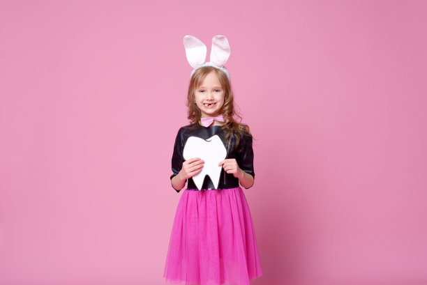 快乐女孩在复活节兔子的形式与布局的人的牙齿。乳牙改为恒牙。医学的概念。牙医的一天。有选择性的重点。图片下载