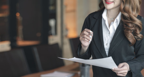 一个女商人站在会议室里，手里拿着笔和纸。图片下载