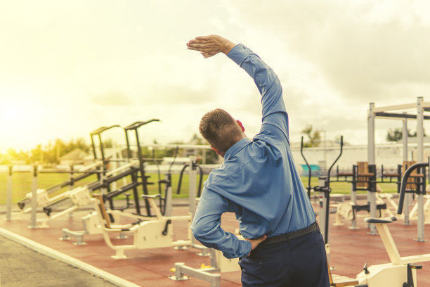 一名身着西装的男子正在体育场的模拟器上热身。下班后进行体育锻炼。与超重的斗争。商人在健身房。图片下载