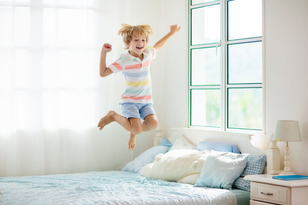 孩子在床上玩耍。孩子的房间。男孩在家里。图片下载