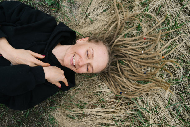 女人喜欢躺在户外的地上。发型风格雷鬼发在草地上同样的颜色图片下载