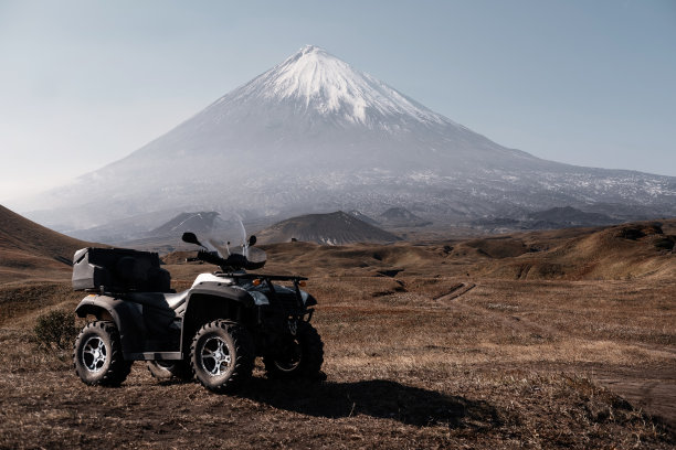 在火山背景上的ATV四轴自行车。kyuchevskaya Sopka，堪察加半岛，越野旅行图片下载