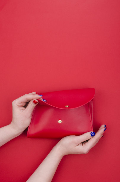 女人手拿鲜亮的指甲握着红色的手包图片下载