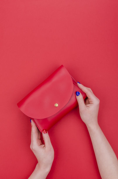 女人手拿鲜亮的指甲握着红色的手包图片下载