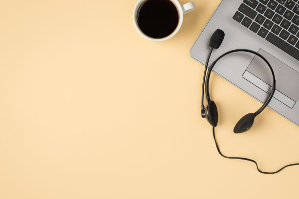 上面的照片笔记本耳机和一杯咖啡孤立的米色背景与copyspace图片下载
