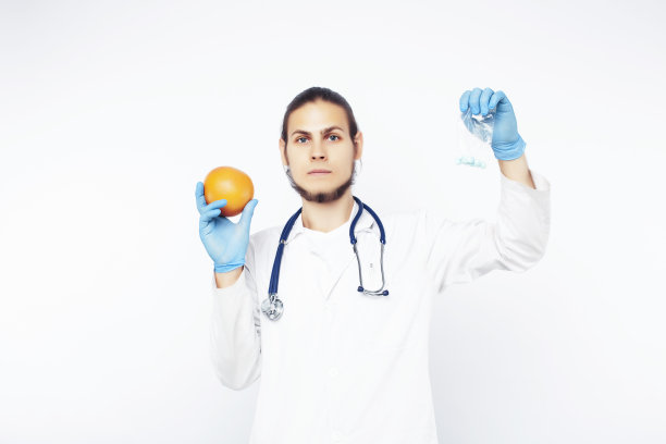 年轻漂亮的医生用听诊器手持水果、蔬菜和药片，注射器，健康的饮食保健理念图片下载