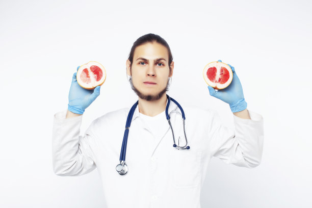年轻漂亮的医生用听诊器手持水果、蔬菜和药片，注射器，健康的饮食保健理念图片下载