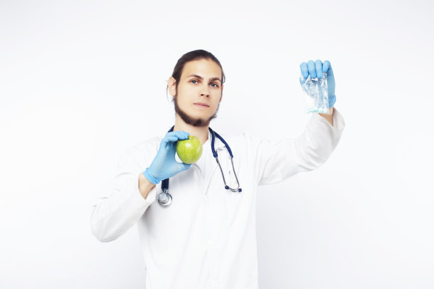 年轻漂亮的医生用听诊器手持水果、蔬菜和药片，注射器，健康的饮食保健理念图片下载