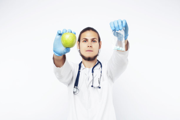 年轻漂亮的医生用听诊器手持水果、蔬菜和药片，注射器，健康的饮食保健理念图片下载