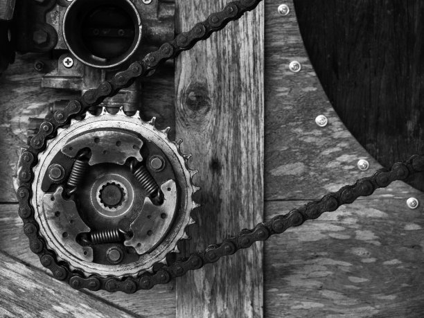 旧生锈齿轮机构安排在木制背景，黑白风格。混合和匹配的背景齿轮，自行车链，机械上的古董木。图片下载
