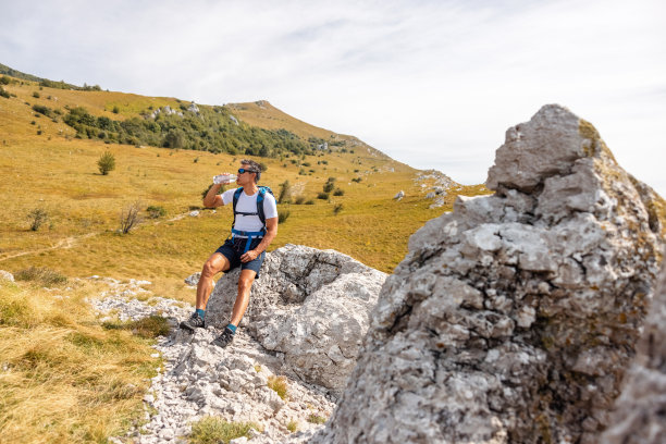 在岩石上休息喝水的徒步旅行者图片下载