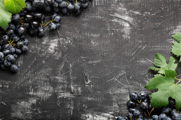 黑葡萄做的框架。在黑色磨损的背景上复制文本或菜单空间。黑色混凝土背景下的黑色多汁葡萄。图片下载