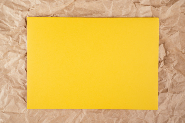 背景图片:皱巴巴的有纹理的牛皮纸，中间是一张黄色的硬纸板。前视图。本空间图片下载