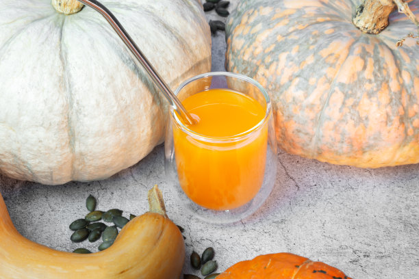 天然蔬菜新鲜橙汁南瓜汁，装在带有金属管的玻璃杯中。健康的食物图片下载