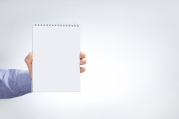 男性手持笔记本在浅灰色背景。实物模型。图片下载