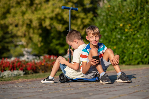 男孩们坐在摩托车上，拿着电话图片下载