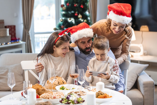 快乐、微笑的父母和他们的孩子坐在餐厅里，在圣诞节度过了美好的时光。图片下载