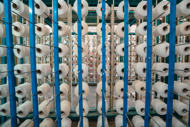 纺织厂工业整经机上按顺序排列的白色线轴、筒管、线筒图片下载