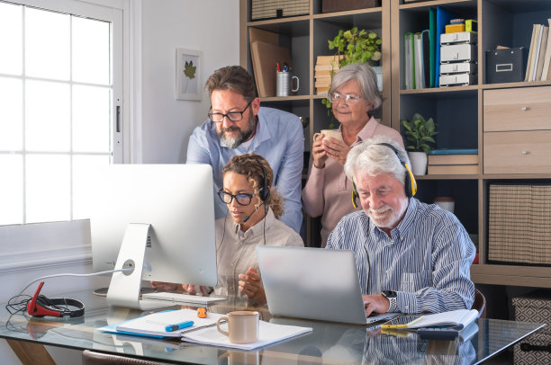 一群商业女性和男性一起用电脑和笔记本电脑工作，坐着的人们戴着耳机图片下载