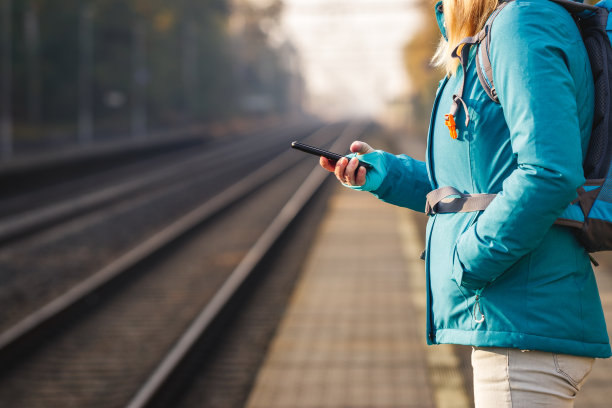一位女士在等火车时使用智能手机图片下载