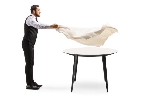 一名服务员将桌布铺在圆桌上的全长侧面照片图片下载