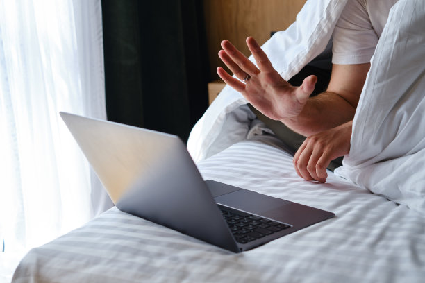 一个商人在床上的笔记本电脑上通过程序和应用程序来进行谈判。用笔记本电脑工作。经营理念。在家工作的自由职业者。在线交流图片下载