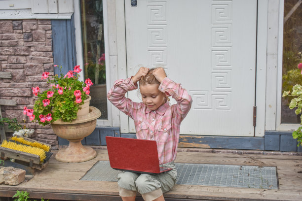 一个女孩带着笔记本电脑坐在房子的门廊上上课，在没有滤镜的远程照片上图片下载