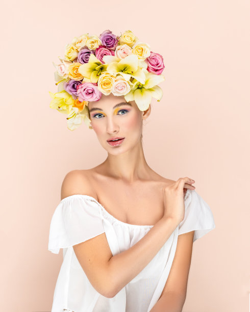年轻漂亮的女人头上戴着一束花。艺术肖像性感金发与五颜六色的花。专业化妆艺术。漂亮的粉色背景。幸福的概念图片下载