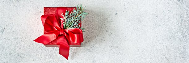 横幅与礼物在一个红色的盒子，装饰与缎带，一个蝴蝶结和圣诞树的小枝在一个浅色的背景。圣诞节、新年概念、极简主义图片下载