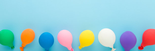 一排彩色的气球在浅蓝色的桌子背景上。柔和的颜色。特写镜头。宽横幅。为鼓舞人心的，积极的文本，可爱的引用或谚语留出空间，为好心情。自顶向下的观点。图片下载