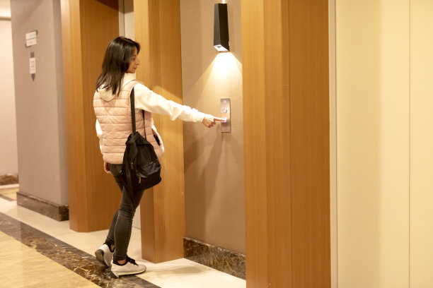 一个女人在按电梯的按钮。图片下载